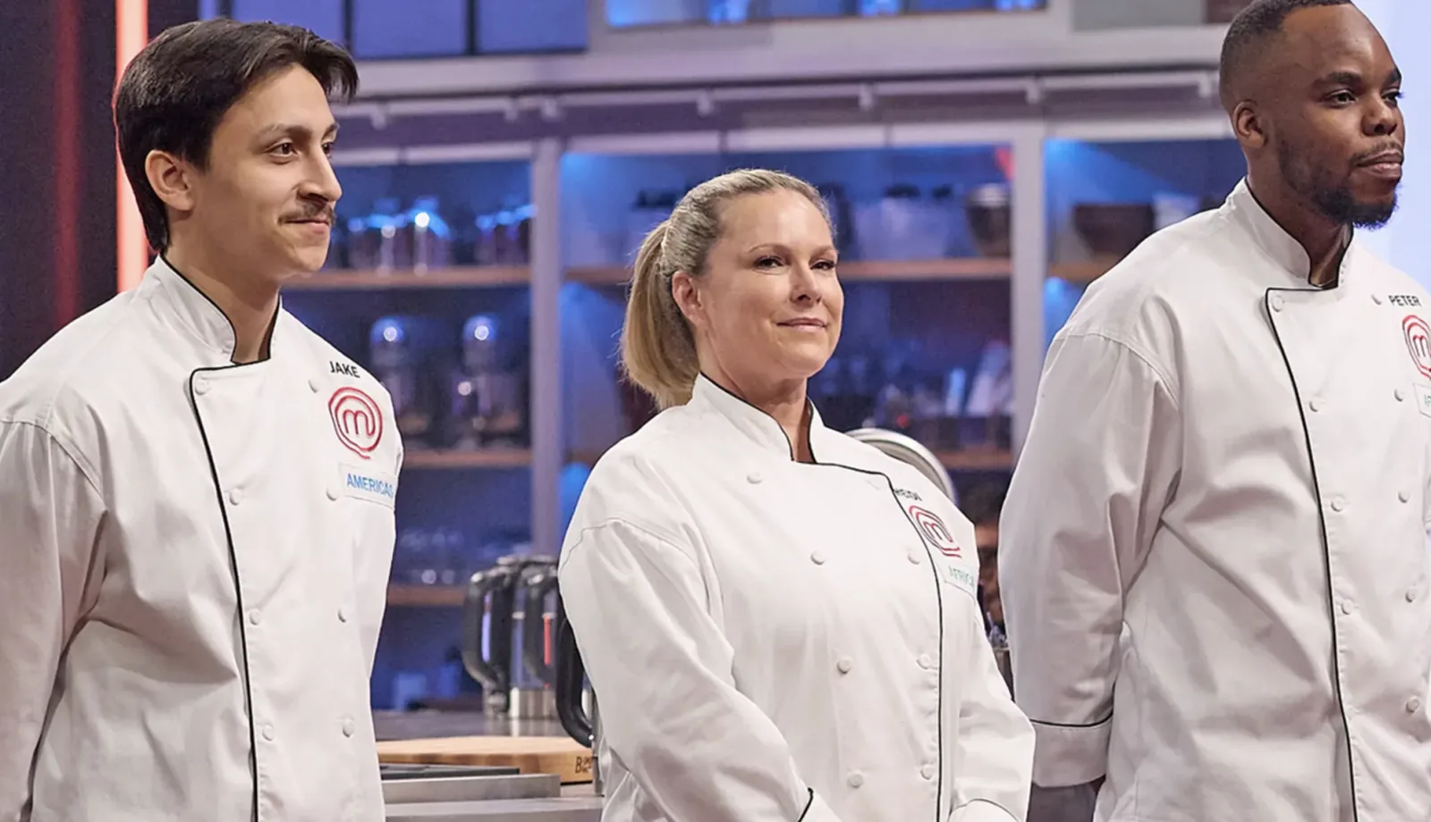 Three contestants in white MasterChef jackets standing on the competition set.