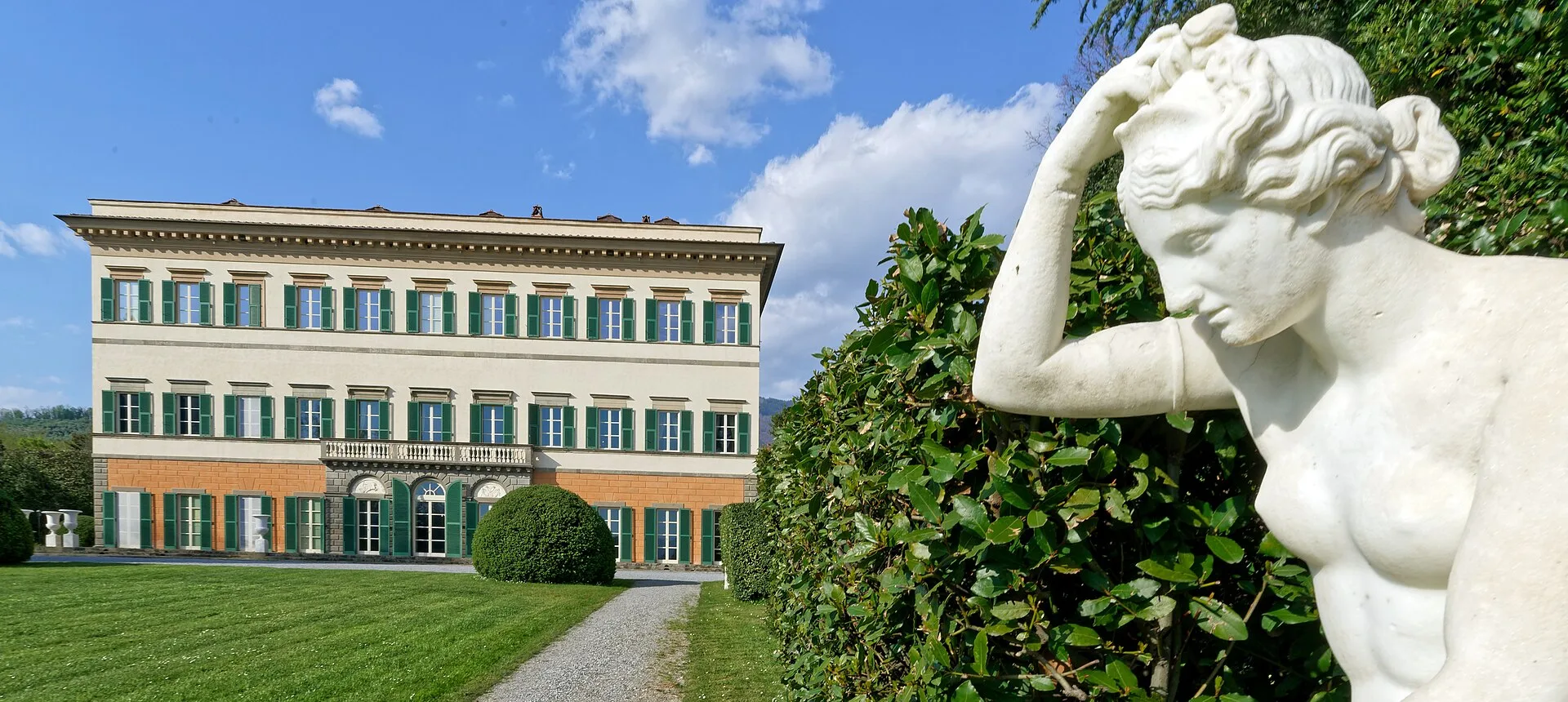 Villa Reale di Marlia with green shutters, lawn and a garden statue.